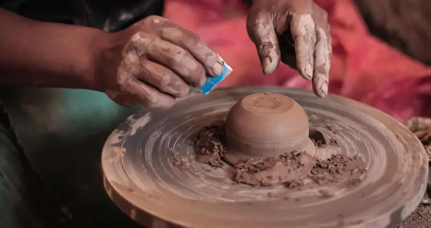 A person skillfully shapes a pot on a potter's wheel, embodying the art of clay healing in Sacred Valley.