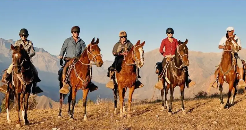 A rider on horseback traverses the scenic highlands of Peru's Sacred Valley, surrounded by stunning mountain landscapes.