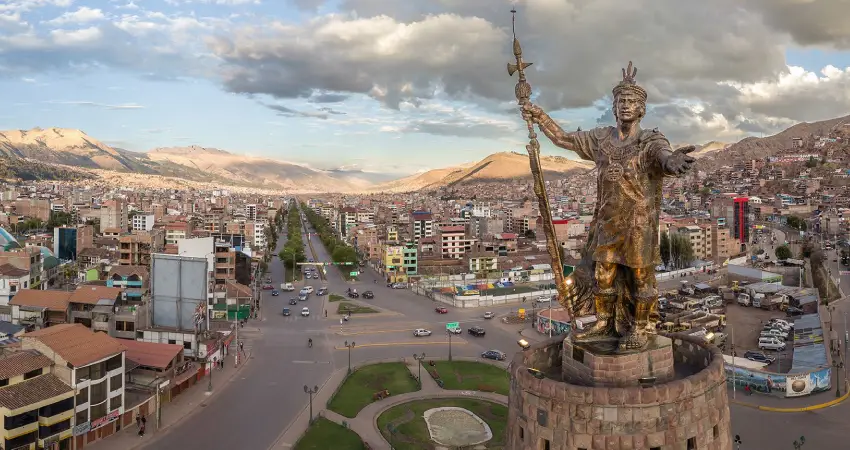 The Inca Pachacutec monument, resembling the Statue of Liberty, stands proudly in a Cusco cityscape.