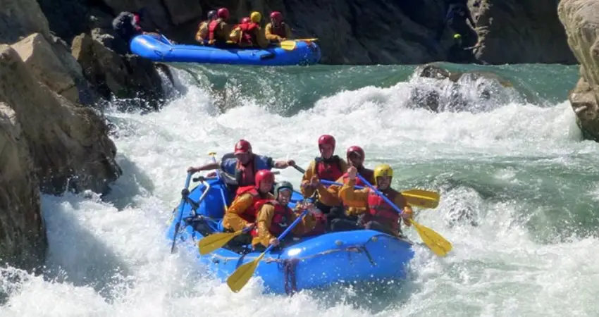 A group of adventurers rafting down a river in Cusco, Peru, surrounded by lush greenery and stunning landscapes.